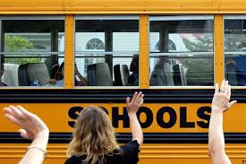 teacher waving to kids on bus